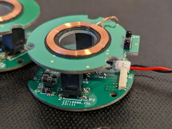 A green sensor circuit board with its copper coil, wired up on the bench